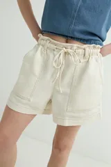 Short de denim azul con cintura elastizada fruncida, cordón de ajuste y bolsillos delanteros parcheados.