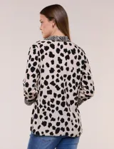 Camisa holgada de rayón con estampado animal print de manchas negras sobre fondo beige, cuello camisero y abotonadura frontal con detalles de estampa estilo cebra. Cuenta con mangas tres cuartos y ruedo curvo.