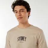 Camiseta beige de manga corta con estampado frontal en negro que dice "SYDNEY AUSTRALIA".