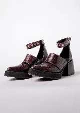 Zapato de cuero color marrón con textura de reptil, con punta fina, corte lateral y pulsera con hebilla y apliques metálicos.