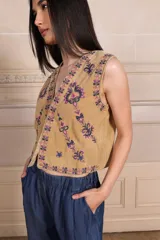 Chaleco sin mangas de terciopelo color tostado, con escote en V y bordados florales en tonos violeta y rosado.