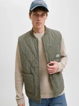 Chaleco acolchado color verde oliva, con diseño de matelassé, cuello estilo baseball y cierre frontal con botones a presión. Cuenta con dos bolsillos frontales y un bolsillo pequeño en el pecho con etiqueta de marca.