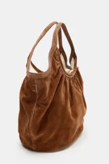 Bolso de hombro formato mini shopper confeccionado en piel, con diseño fruncido, doble asa de mano con pespuntes decorativos y cierre mediante clip metálico.