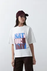 Remera de manga corta con corte boxy fit, color blanco, con estampa frontal geométrica en tonos azul, rosado y marrón.
