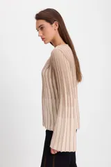 Sweater de punto con diseño de rayas verticales en dos colores, azul y crudo. Presenta cuello bote, mangas largas con terminación acampanada y un aplique decorativo en el pecho.