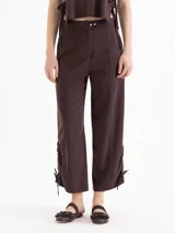 Pantalón marrón de tiro medio, con fit relajado, pierna ancha y efecto babucha. Confeccionado en twill importado, cuenta con bolsillos laterales, bolsillos traseros tipo ojal, presillas en la cintura y detalles de lazos fruncidos en los laterales.