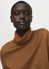 Sweater de punto fino color mostaza, con cuello alto y mangas largas de diseño recto.