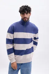 Buzo deportivo de hombre con medio cierre, cuello alto y bloques de color azul y beige en rayas horizontales.