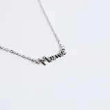 Collar de plata 925 con dije de nombre en cursiva que dice 'Mamá', sujeto a una cadena de eslabones finos.