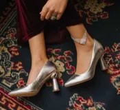 Zapato de tacón plateado, con punta fina y taco con forma de esfera.