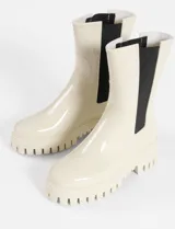 Botas de lluvia de caña media con acabado brillante, diseño tipo chelsea con paneles laterales elásticos en color negro y suela track dentada de plataforma.