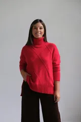 Polerón de punto color rojo con cuello alto y diseño de rombos texturizados. Presenta mangas largas con puños acanalados y un corte holgado con ruedo asimétrico.