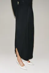 Pantalón de tiro medio confeccionado en hilatura de viscosa, de pierna ancha con pinzas en el delantero y bajo con abertura lateral. Cierre con cremallera oculta en costura.