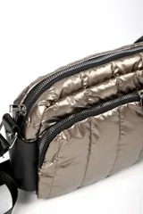 Cartera tipo bandolera de diseño acolchado en color plateado metalizado. Cuenta con dos compartimentos principales con cierre, detalles en negro y correa ajustable extraíble.