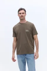 Remera de manga corta color verde oliva, con cuello redondo y calce regular. Presenta un pequeño estampado tipográfico en el pecho con la frase 'Ethereal mountains'.