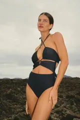 Traje de baño entero negro de lycra brillante, con escote cruzado tipo bikini y bombacha vedetina.