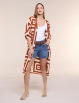 Cardigan largo confeccionado en tejido de punto calado estilo crochet, con diseño geométrico en tonos tostado y crudo, frente abierto sin botones y mangas amplias tipo kimono de tres cuartos.