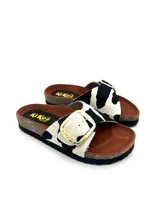 Sandalias bajas con base de corcho y tira ancha de pelo con estampado de vaca y hebilla dorada.