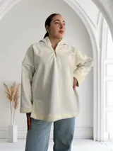 Buzo blanco de ecocuero con capucha, cierre dorado a mitad del frente y puños con forro de piel sintética.