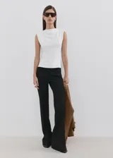 Camiseta sin mangas de color blanco, de diseño recto, con cuello redondo y hombreras, con corte peplum en la parte inferior.