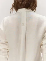 Camisa de lino liviano color tostado, con silueta relajada, cuello mao, alforzas verticales frontales, mangas con volumen y puños elastizados con volados.