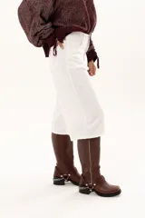 Bermuda de corte recto y tiro alto, confeccionada en gabardina blanca, con cierre frontal de botón y cremallera, y bolsillos laterales.