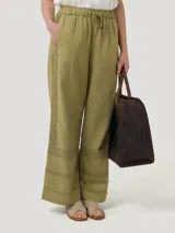 Pantalón de lino orgánico y viscosa color crema, de tiro alto y corte recto, con pinzas delanteras, bolsillos laterales y detalle de trabilla ajustable con hebilla metálica en la cintura.
