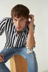 Camisa de mangas largas con estampado a rayas verticales en tonos verde oliva, blanco y azul. Corte regular y logo bordado en el pecho. Confeccionada en viscosa.