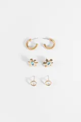 Set de tres pares de aros dorados que incluye aros tipo argolla texturizada, aros con diseño de flor y centro de piedra celeste, y aros pequeños circulares tipo botón.