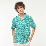 Camisa de manga corta con cuello cubano y estampado de hojas abstractas en blanco sobre fondo verde.