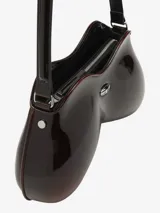 Bolso de hombro para mujer de Diesel, color negro, con forma orgánica y brillante, similar a un control de videojuegos. Posee un asa de hombro negra y un pequeño dije metálico con logo en el frente.