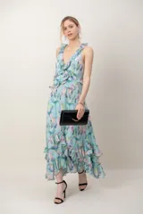 Vestido largo de gasa verde agua con estampado floral en tonos pastel, escote en V profundo, espalda cruzada con tirantes regulables y detalles de volados en los tirantes y en el ruedo.