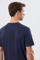 Remera azul marino de manga corta con cuello redondo, confeccionada en mezcla de algodón y poliéster. Presenta un diseño en el frente que combina estampa y bordado con la leyenda "Legacy Brand 1972" en tonos rosado, verde y marrón.