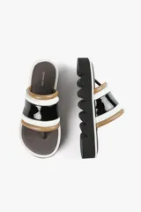 Sandalia con base alta y diseño de líneas audaces. Presenta capellada ancha con acabado brillante y estructura acolchada que aporta confort al andar. La suela dentada le da un carácter urbano y moderno, sin resignar comodidad.