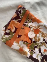 Pañuelo cuadrado de seda con estampado floral en tonos naranja, borra de vino, beige y blanco.