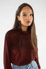 Remera de manga larga con cuello polera, confeccionada en tejido brillante con acabado metalizado en color bordó. Presenta un ajuste regular.