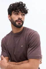 Remera básica de hombre con escote redondo y manga corta. Presenta un diseño liso en color marrón con un pequeño logo bordado en el pecho.