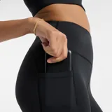 Calza deportiva negra de tiro alto, con bolsillos laterales y detalles reflectivos en el dobladillo. Confeccionada con tejido elástico NB Sleek que se adapta a la figura y tecnología NB DRY de secado rápido.