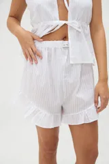 Short de pijama blanco con textura a rayas sutiles, cintura elástica con etiqueta de la marca y detalle de volados en el ruedo.