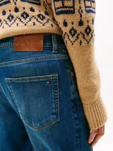 Jean de corte recto clásico, confeccionado en denim azul con lavado medio. Presenta diseño de cinco bolsillos, cierre con botón y cremallera, y detalles distintivos de la marca.