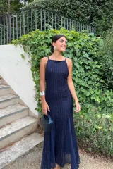 Vestido largo azul marino de Lady Pipa, con tirantes finos y escote cuadrado. El diseño es ajustado al cuerpo con una falda que se abre en la parte inferior, y presenta un tejido brillante con rayas verticales.