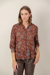 Camisa de manga larga con estampado de leopardo, cuello clásico y cierre frontal de botones. Presenta un corte holgado y puños abotonados.