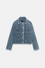 Chaqueta de denim de corte clásico con textura perforada, cuello solapa, bolsillos delanteros de plastrón, cierre frontal con botones a contraste y detalles de flecos en los bordes.