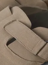 Zueco tipo mule de gamuza color taupe, con puntera redonda, tira ajustable con velcro y suela de corcho con base de goma.