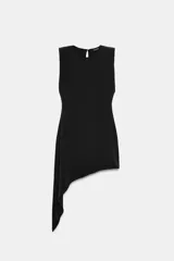 Vestido corto negro sin mangas con hombreras, cuello redondo y bajo asimétrico con una caída lateral más larga. Cuenta con cierre en la espalda con abertura y botón.