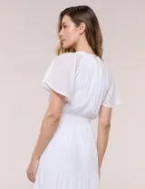 Vestido midi blanco de calce suelto y caída fluida, con escote en V, cuello a la base y apertura abotonada con detalle de puntilla. Cuenta con cintura elastizada con lazo para anudar a tono, mangas cortas con volados y falda con volantes escalonados.