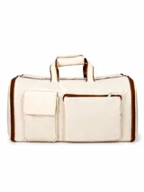 Bolso de viaje color beige con detalles en marrón, cuenta con dos bolsillos frontales, uno con solapa y otro con cierre, y manijas superiores reforzadas.