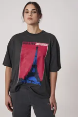 Remera de algodón color gris con efecto lavado, de corte oversize y cuello redondo. Presenta una estampa gráfica frontal con la Torre Eiffel y el texto 'Satori in Paris Jack Kerouac'.
