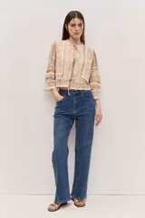 Blusa tostada con mangas tres cuartos, detalles de encaje floral calado y cierre frontal con lazos.