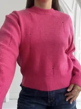Sweater fucsia de punto con cuello redondo y detalles rotos.
